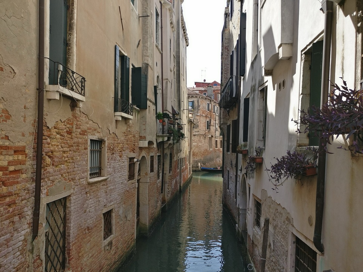 A small side canal — a rio — between brick walls, with a moored boat